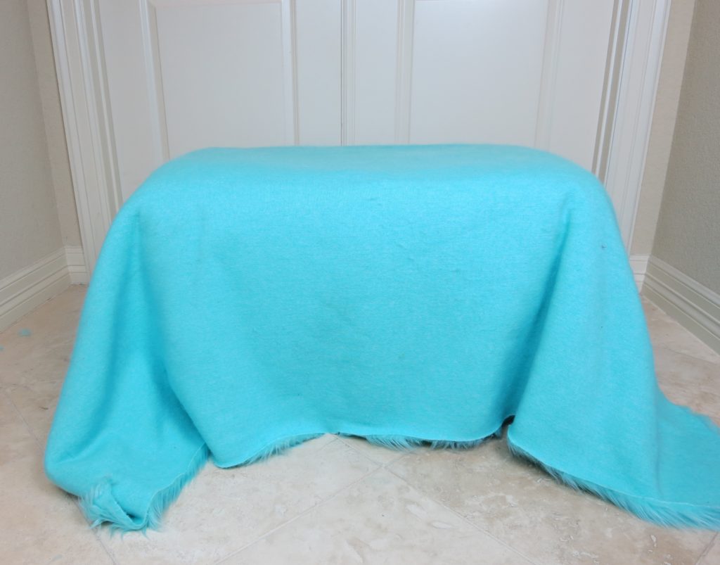 For example, if you measure 48" from the front to the back of the ottoman and 36" from one side to the other side, then you will cut a rectangle of fur fabric that is 48x36 inches. I used approximately 2 yards of fabric for my ottoman makeover.